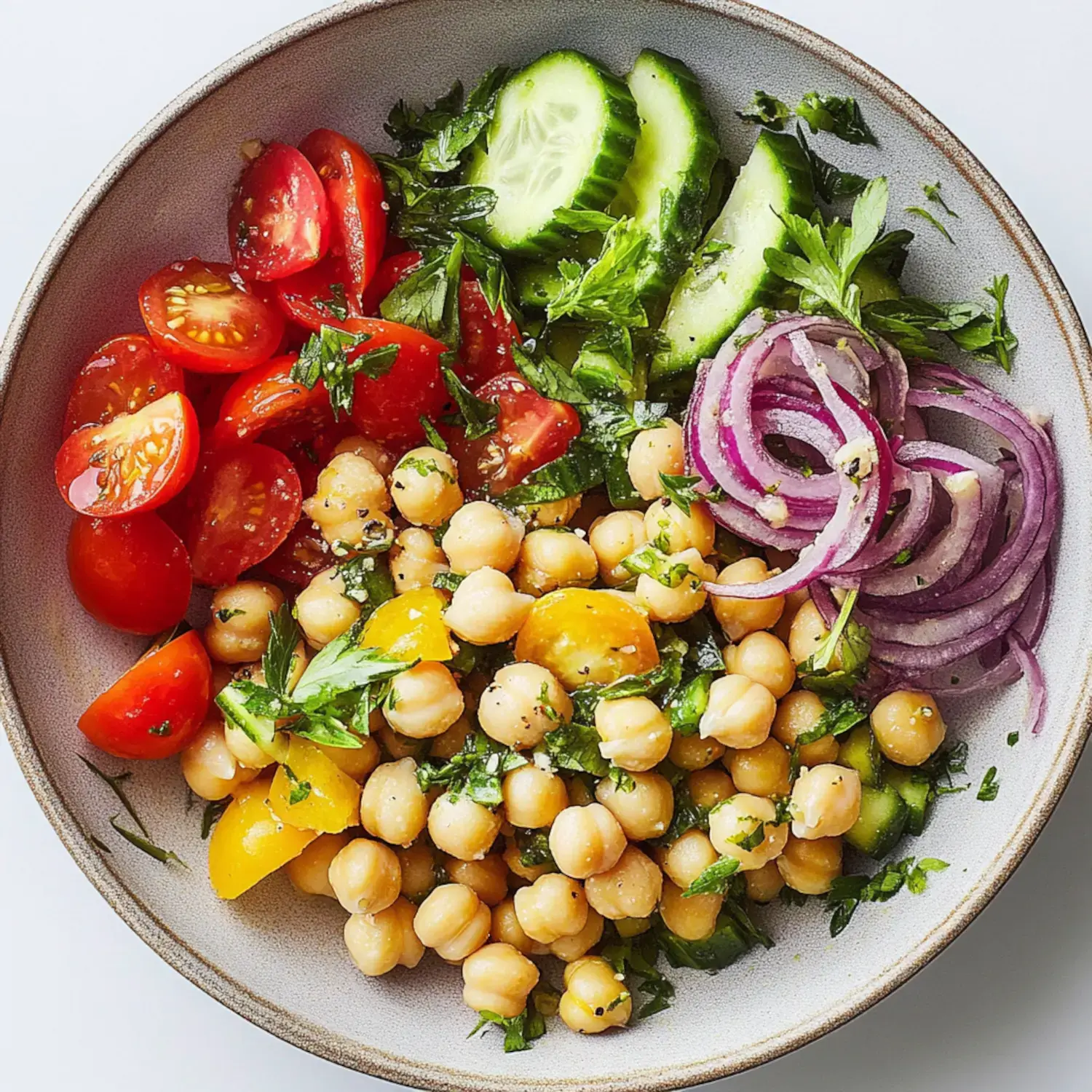 A bowl of chickpeas mixed with chopped tomatoes, cucumbers, red onions, and fresh parsley.