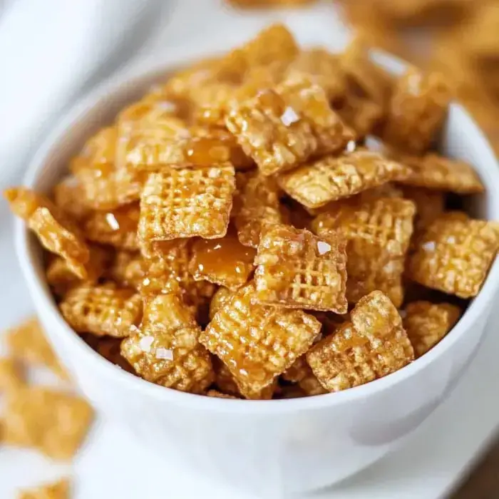 A bowl of golden, textured cereal pieces coated in a sticky, sweet glaze and sprinkled with salt.