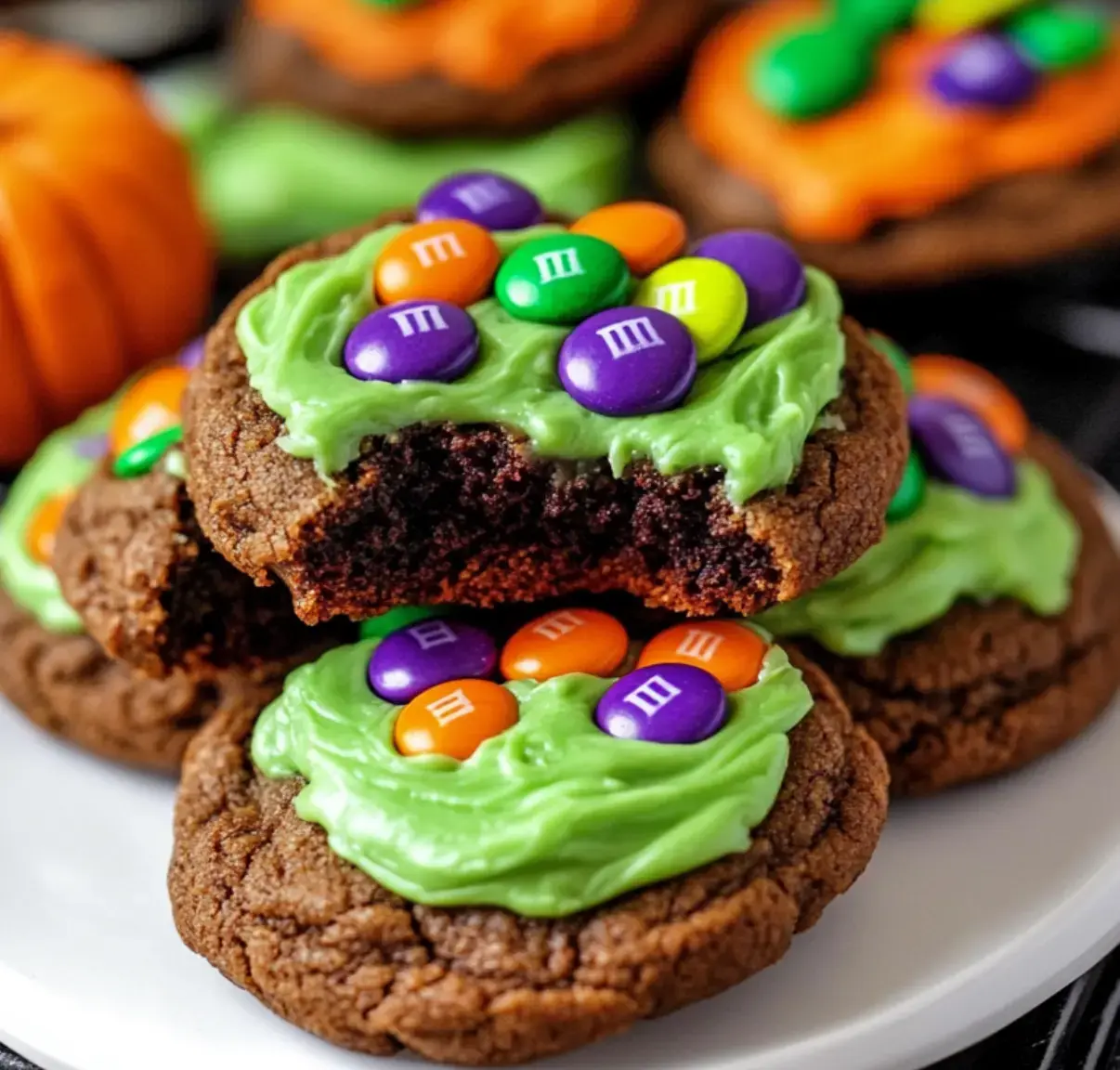 A plate of chocolate cookies decorated with vibrant green frosting and colorful candy, resembling a festive Halloween treat.