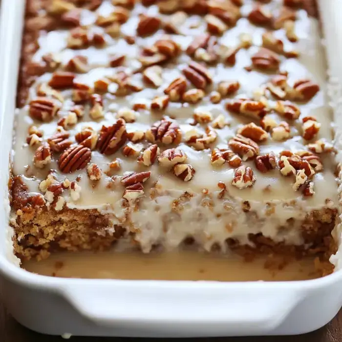 A close-up of a creamy dessert topped with chopped pecans in a baking dish.