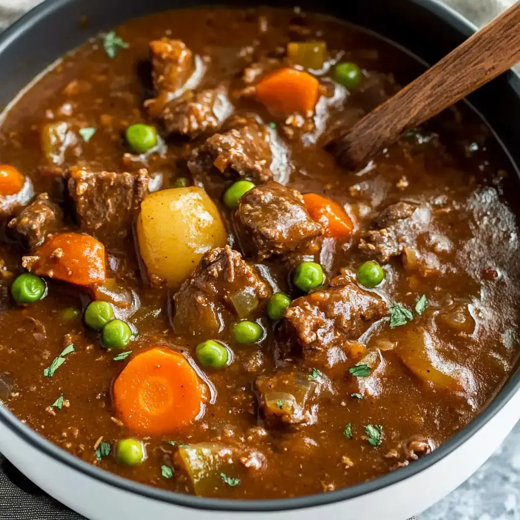 A hearty beef stew with chunks of meat, carrots, potatoes, and peas in a rich, savory broth.