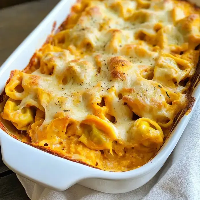 A creamy baked pasta dish with tortellini, topped with melted cheese and seasoned with black pepper.