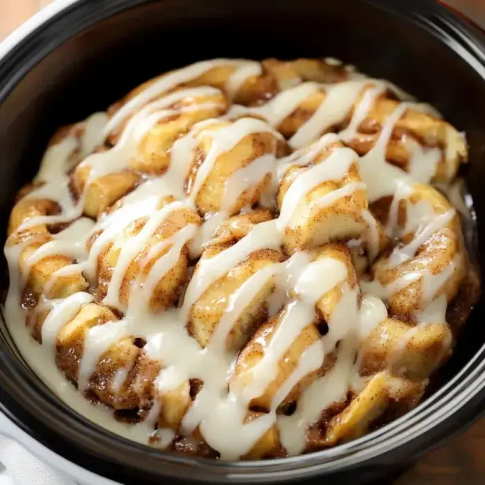 A close-up of a bowl of cinnamon roll pieces drizzled with cream cheese frosting.