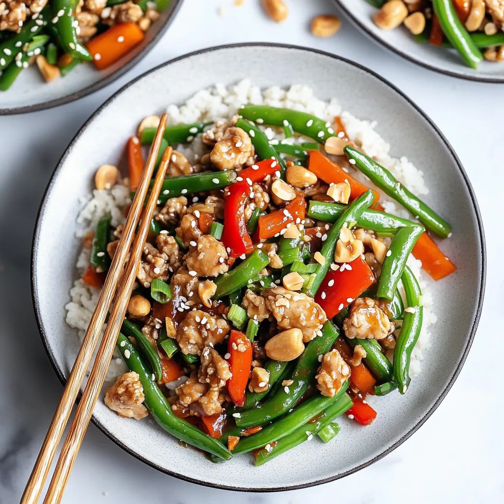 A vibrant plate of chicken and veggies like green beans and peppers served alongside chopsticks.