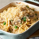 A creamy pasta dish topped with breadcrumbs, mushrooms, and peas in a baking dish.