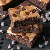 A stack of moist, chocolate brownie bars topped with chocolate chips and surrounded by scattered chocolate pieces.