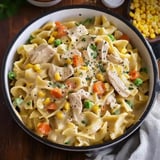 A creamy chicken and pasta dish with peas, carrots, and corn, served in a bowl.