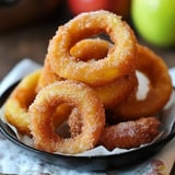 A plate of golden, sugared cinnamon apple rings stacked neatly, showcasing a delicious dessert option.