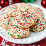 A plate of festive cookies adorned with white icing and colorful red and green sprinkles.