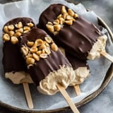 A plate of chocolate-dipped ice cream bars topped with chopped peanuts.