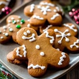 A plate of decorated gingerbread cookies, including one shaped like a gingerbread man with white icing details and colorful sprinkles.